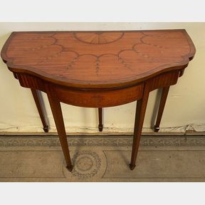 A SUN BURST TOPPED SATINWOOD FOLD OVER CARD TABLE, with serpentine shaped top decorated with beautiful inlaid
