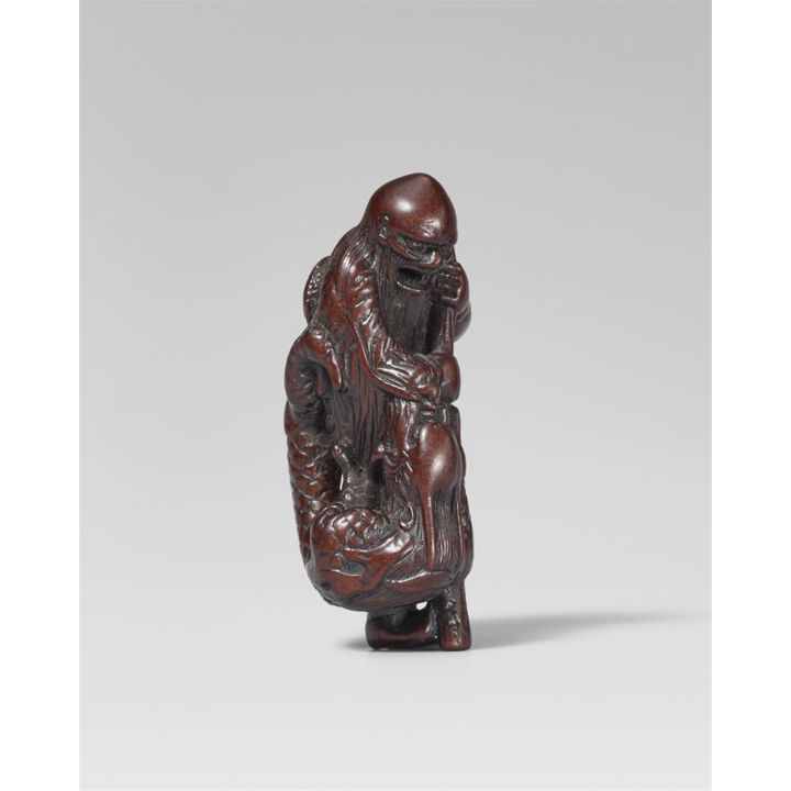 A wood netsuke of a sennin with a dragon. First half 19th century