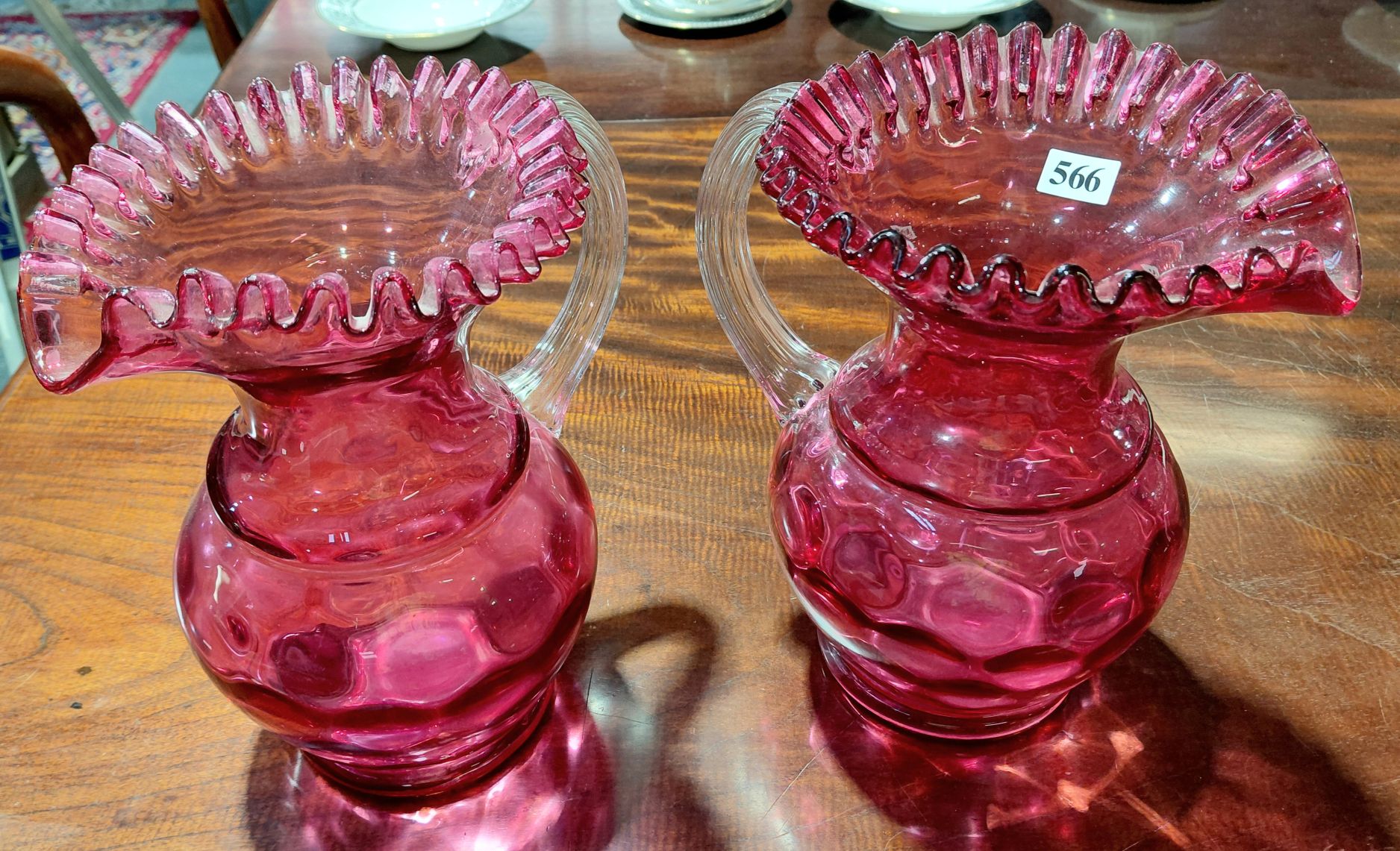 566 · A PAIR OF EDWARDIAN RUBY GLASS JUGS