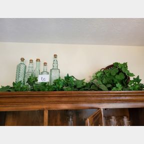 Decorative bottle and greenery on top of China cabinet