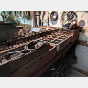 Wooden crates of antique bolts, all thread, pulleys, and steel stock