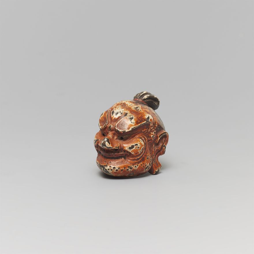 A small painted wood netsuke of a gigaku mask. Early 20th century