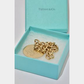 A TIFFANY & CO 14CT YELLOW GOLD CHARM BRACELET with 14ct yellow gold crest charm, marked 14K, and Tiffany & Co