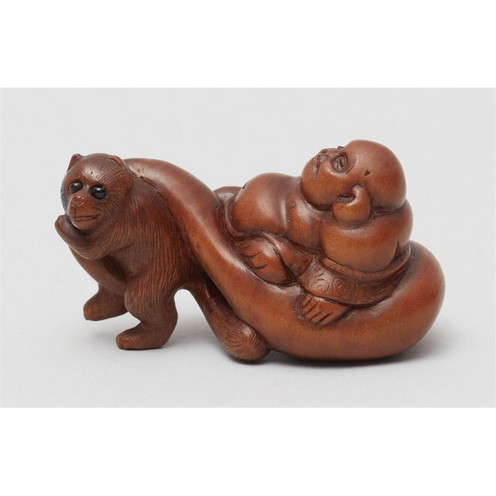 A boxwood netsuke of Hotei being pulled by a tanuki. 19th century