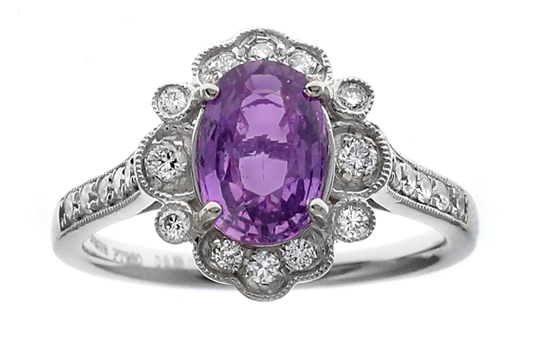 A Pink Sapphire and Diamond Ring The oval cut pink sapphire weighing 1. ...