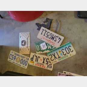 Assorted license plates and metal cowboy toilet paper hanger