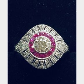 A RADIANT 18CT WHITE GOLD BOMBAY STYLE RUBY & DIAMOND RING, the central bezel set diamond weighs .50cts and is
