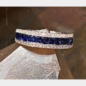 AN 18CT WHITE GOLD CEYLON SAPPHIRE & DIAMOND HALF ETERNITY RING, with a row of diamonds set above and beneath