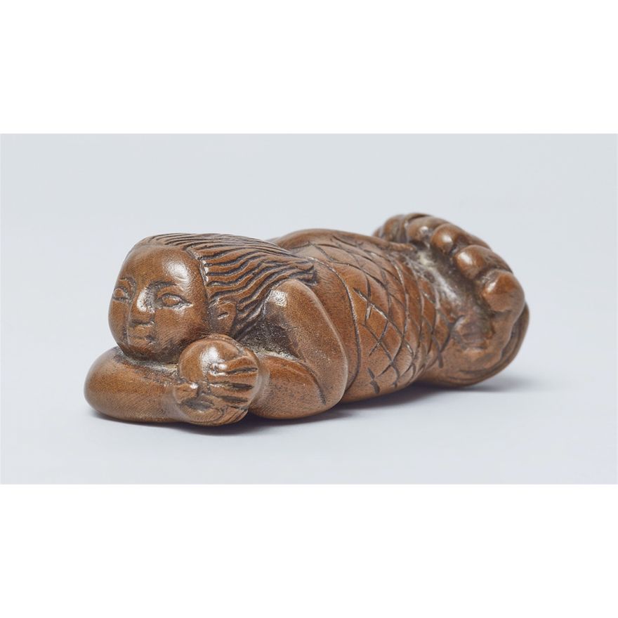 A large wood netsuke of a ningyo with a tama. Early 19th century